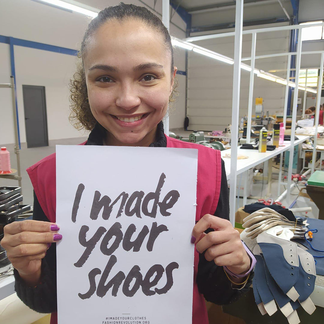 A woman in Trash Planet's vegan sneaker and trainer factory holding up an ethical fashion revolution "I Made Your Shoes" Poster