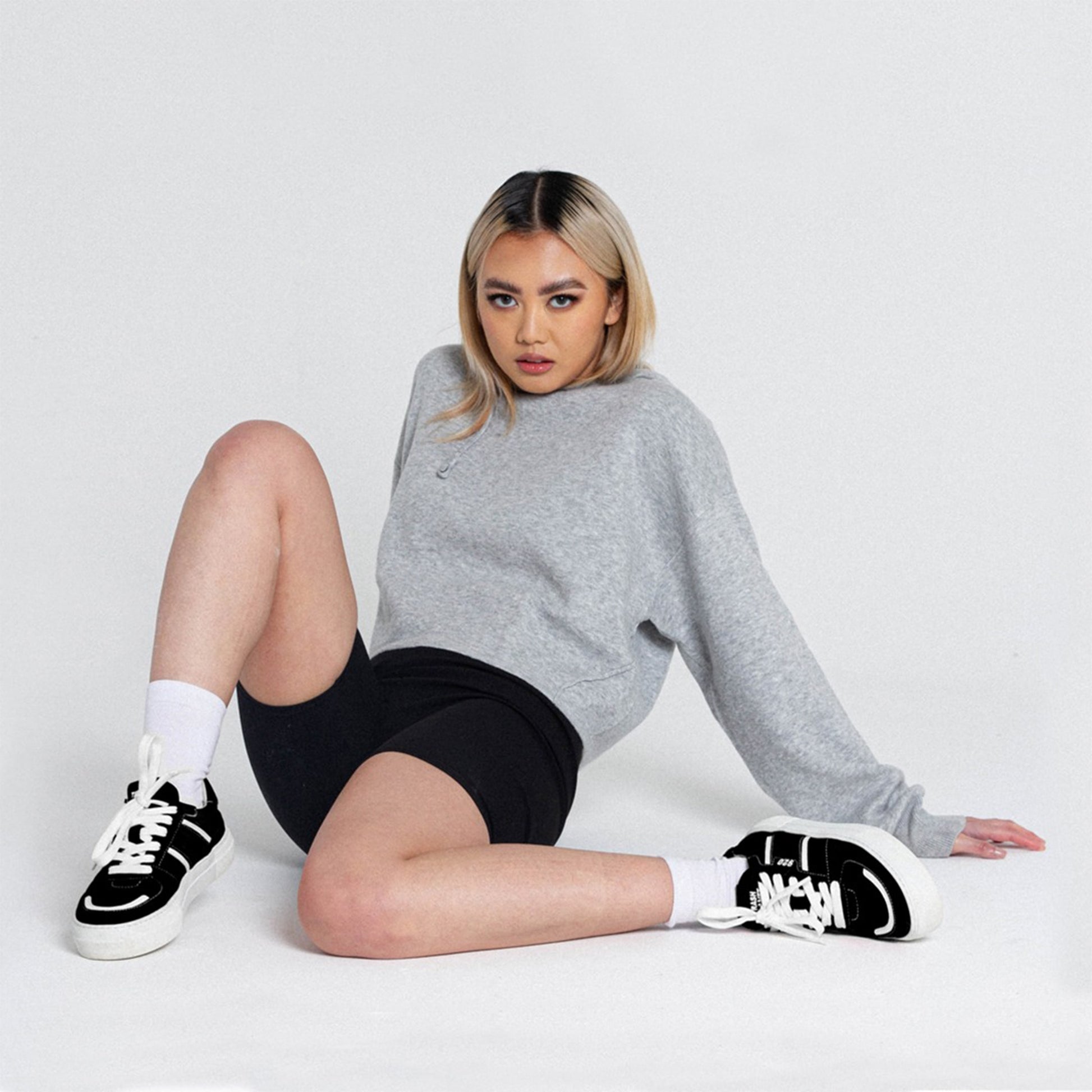 Cool streetwear girl sat on a floor in a studio wearing chunky platform vegan skate sneakers made from trash
